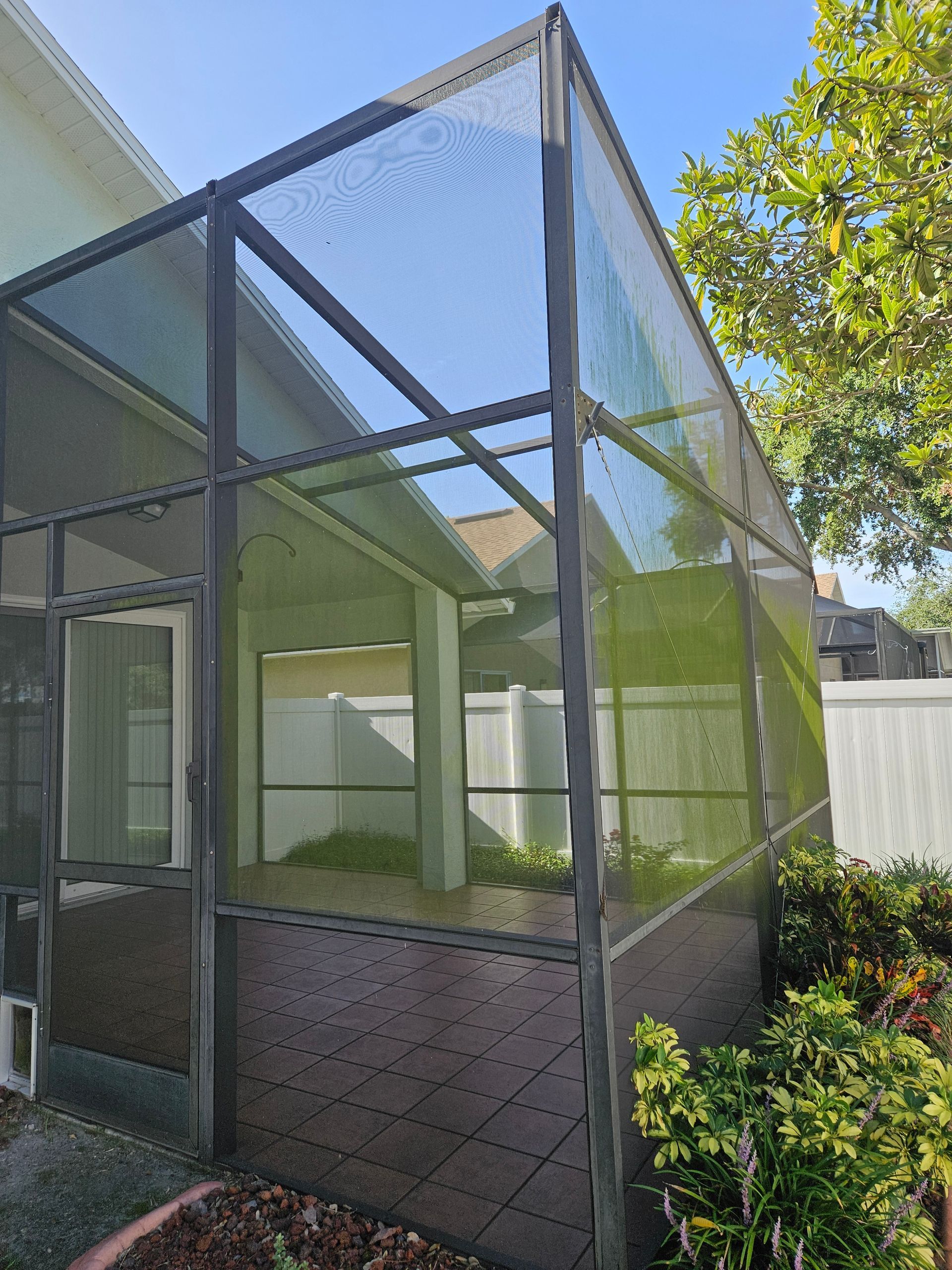 A screened in porch in the backyard of a house.