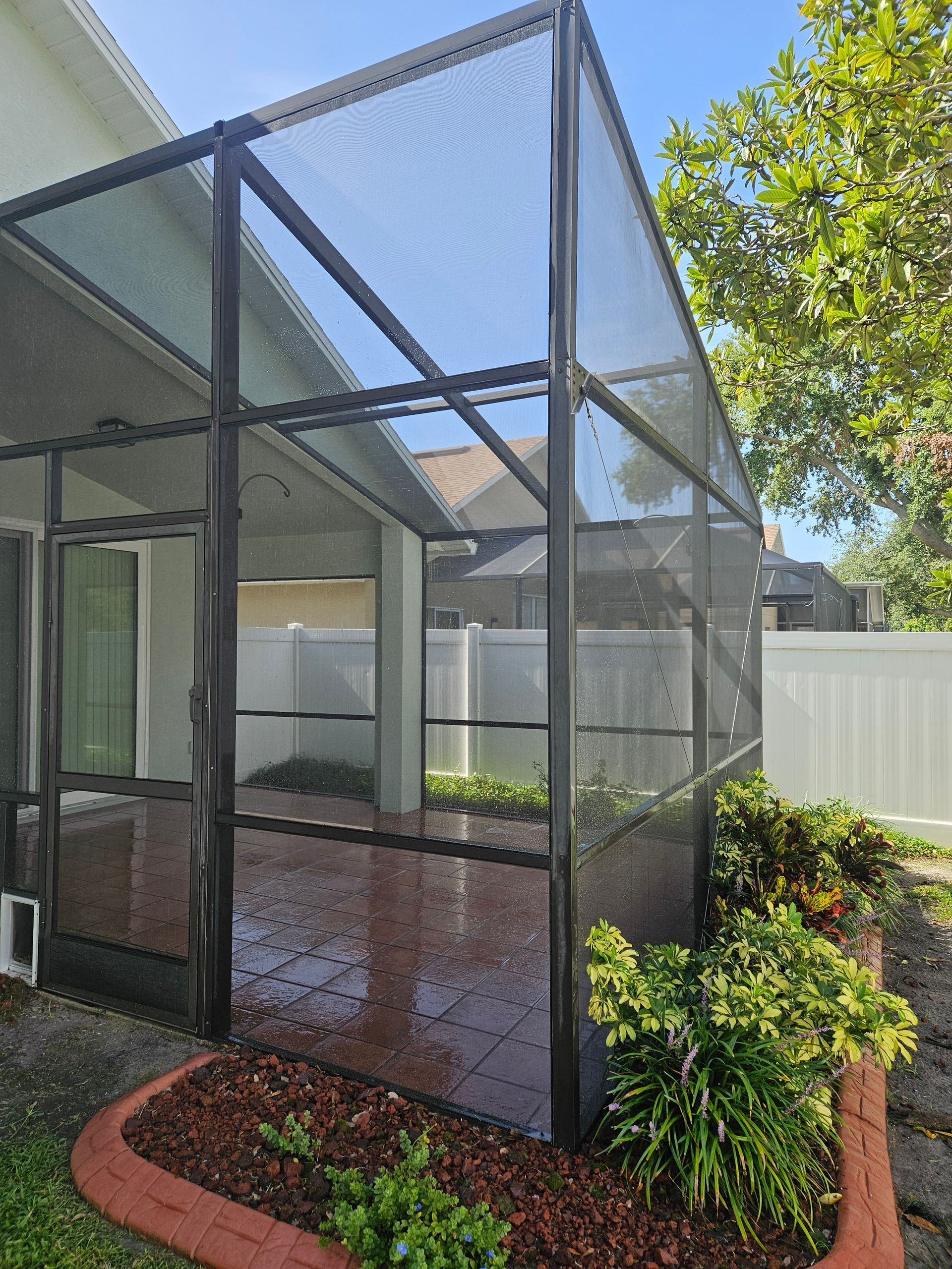 A screened in porch in the backyard of a house.