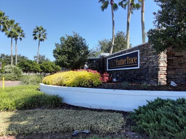 Sign for Panther Trace community with landscaping and palm trees.