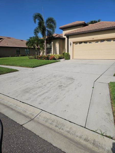 Two-story beige house with a two-car garage, driveway, and palm trees in front.
