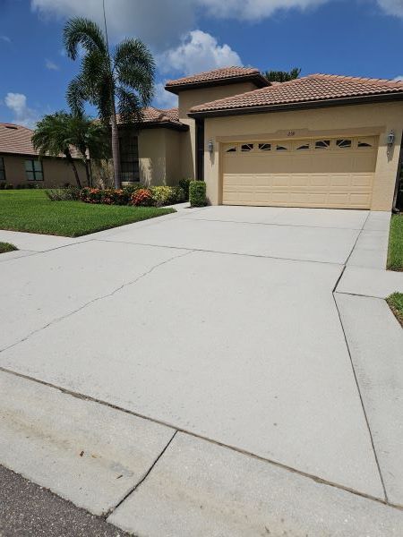 Two-story beige house with a two-car garage, driveway, and palm trees in front.