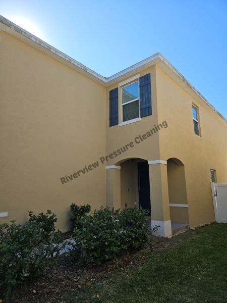 Yellow house with white columns, brown roof, and green lawn.
