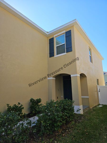Yellow house with white columns, brown roof, and green lawn.