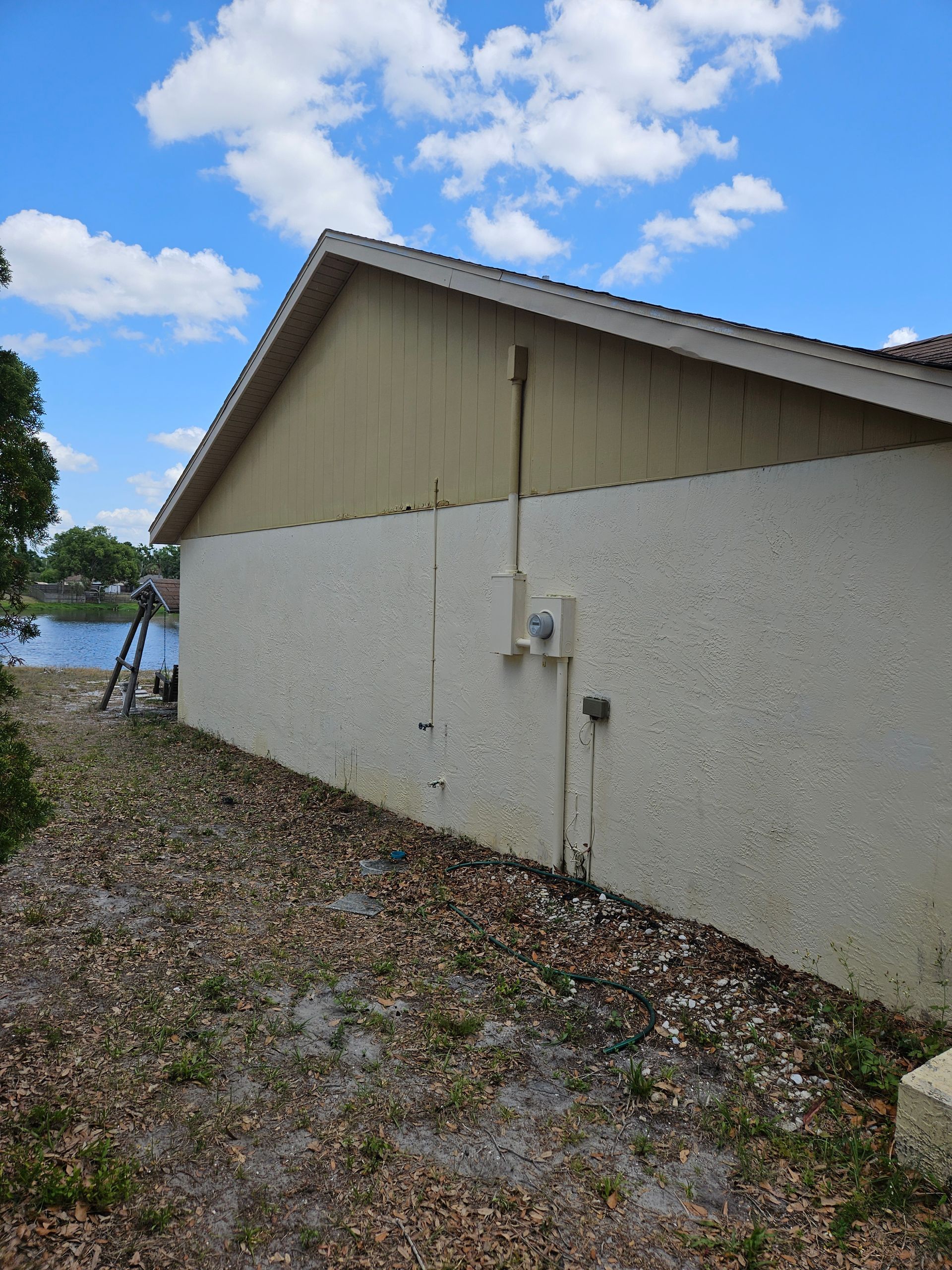 A house with a ladder in front of it and a lake in the background