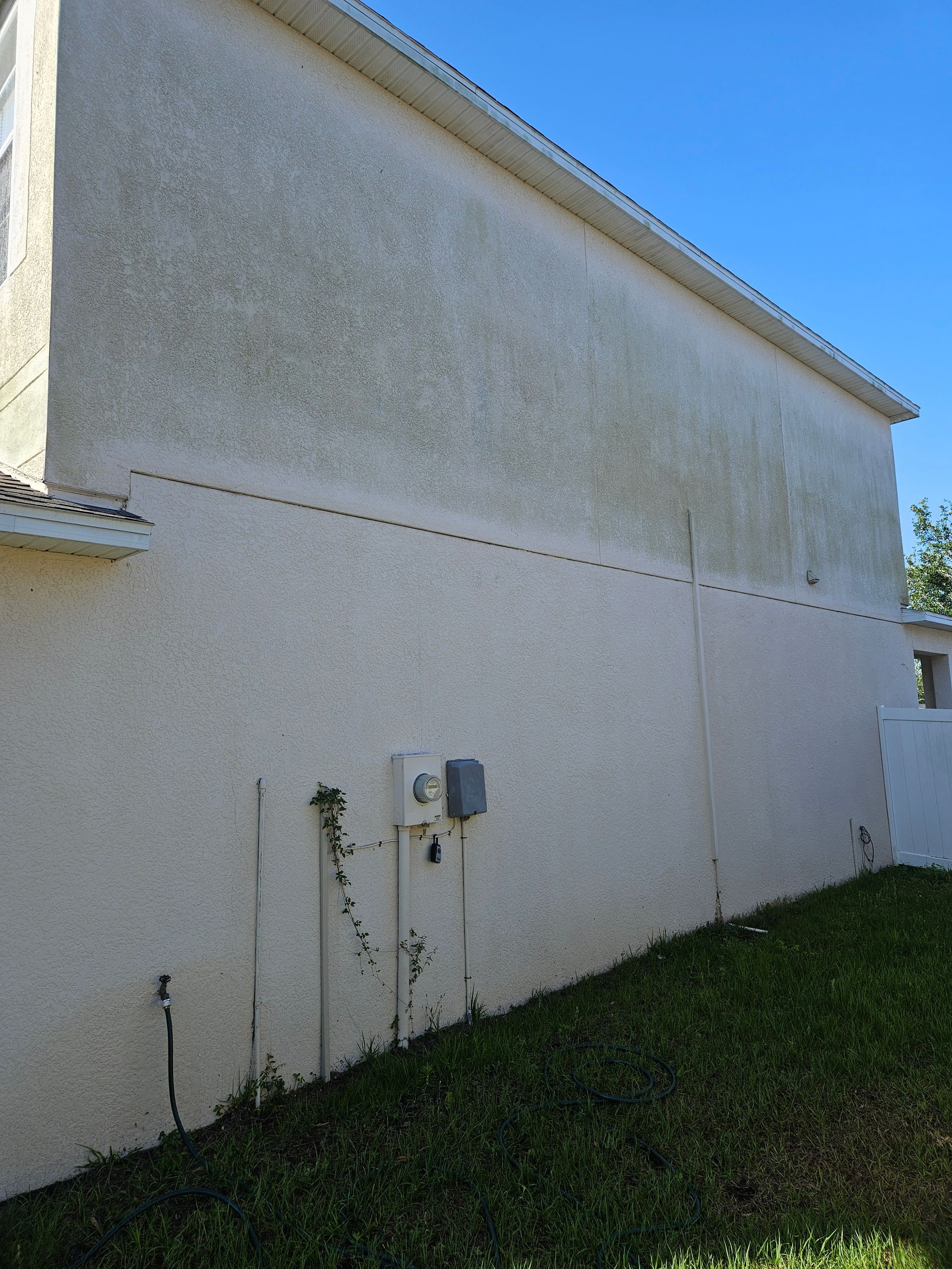A white building with a blue sky in the background is sitting on top of a lush green field.