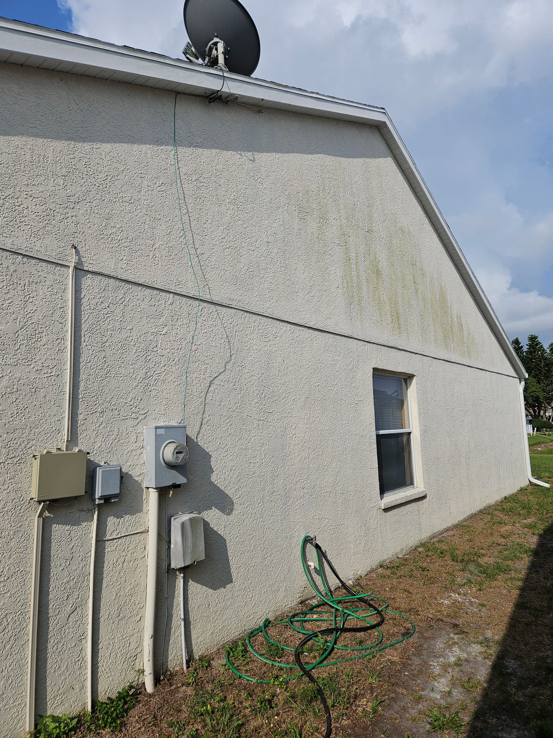 The side of a house with a satellite dish on the roof.