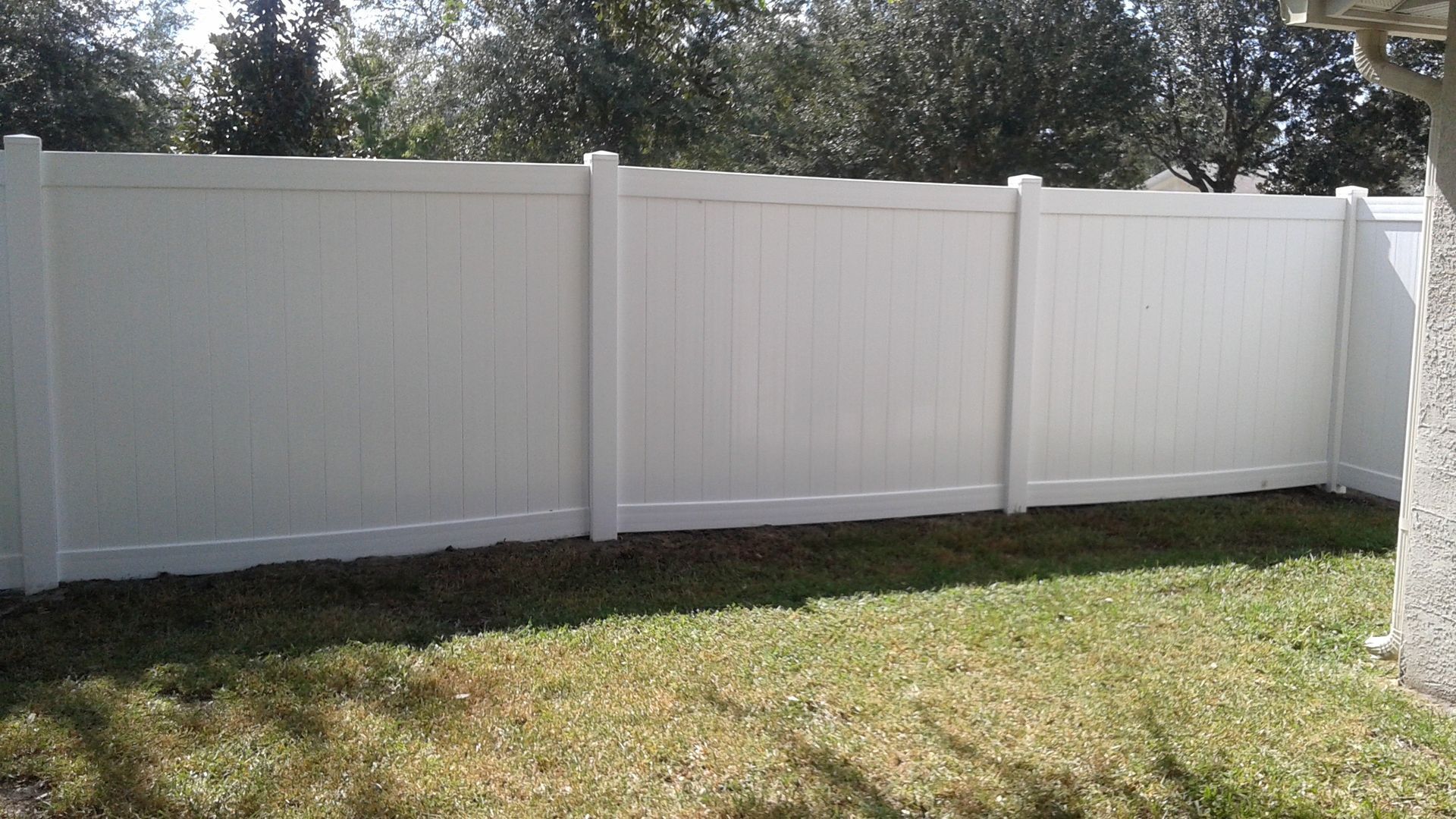 A white fence is in the middle of a lush green yard.