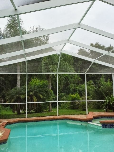 A swimming pool under a clear roof with trees in the background