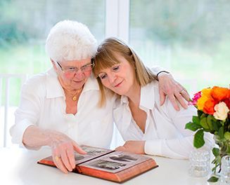 Two women are sitting at a table looking at a photo album.