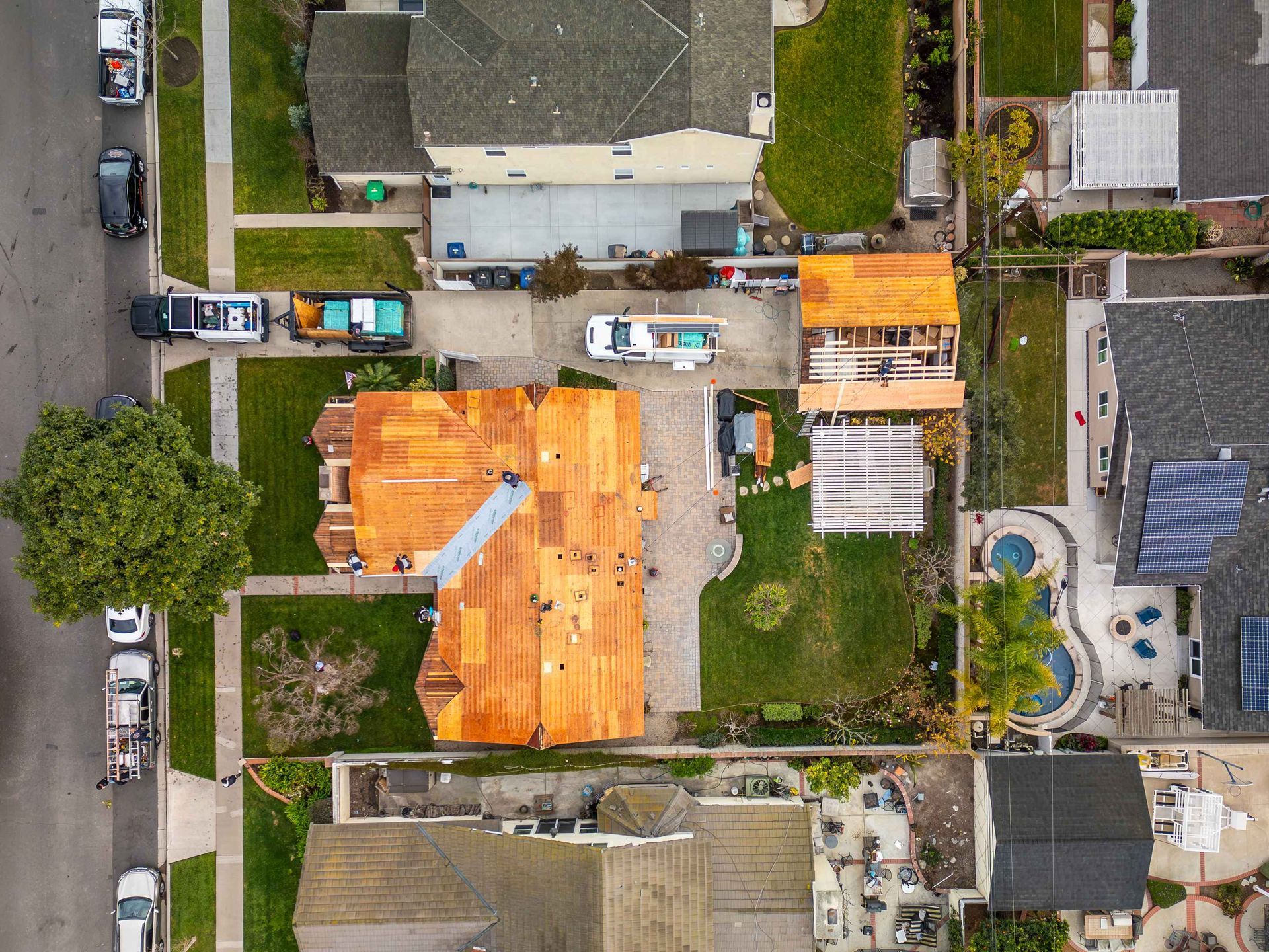 Aerial view of a home with roof renovation. Orange shingles partially cover the roof.