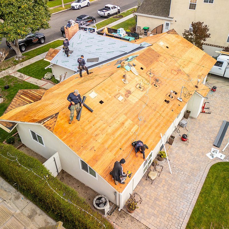 A group of people are working on the roof of a house.