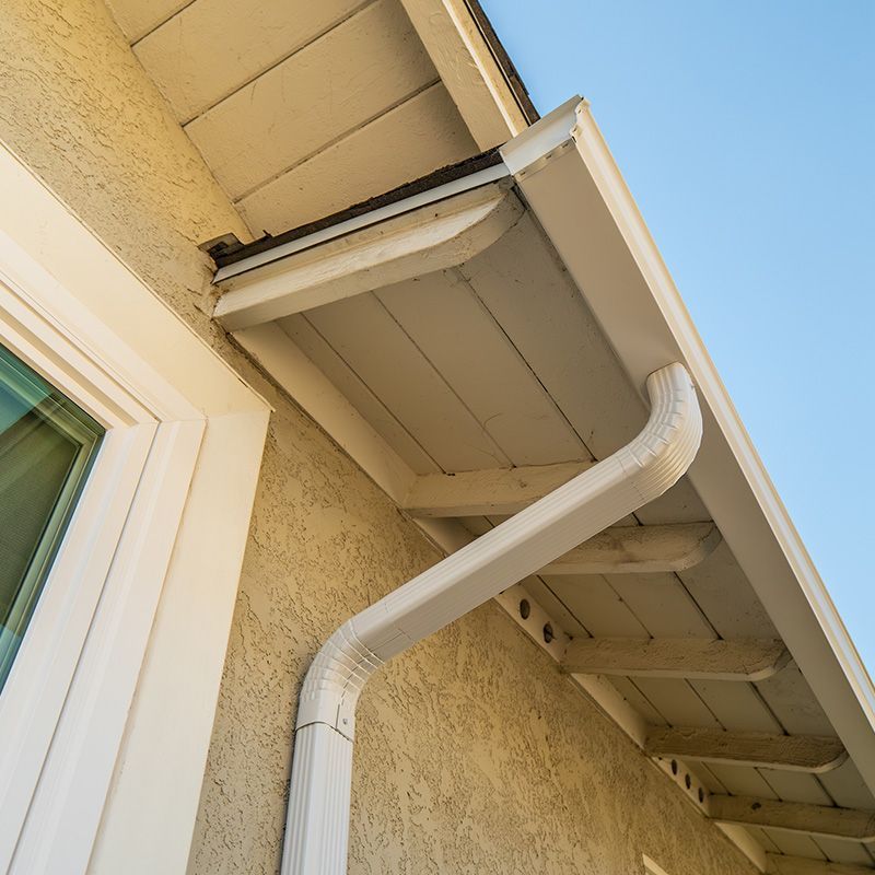A white gutter is attached to the side of a house