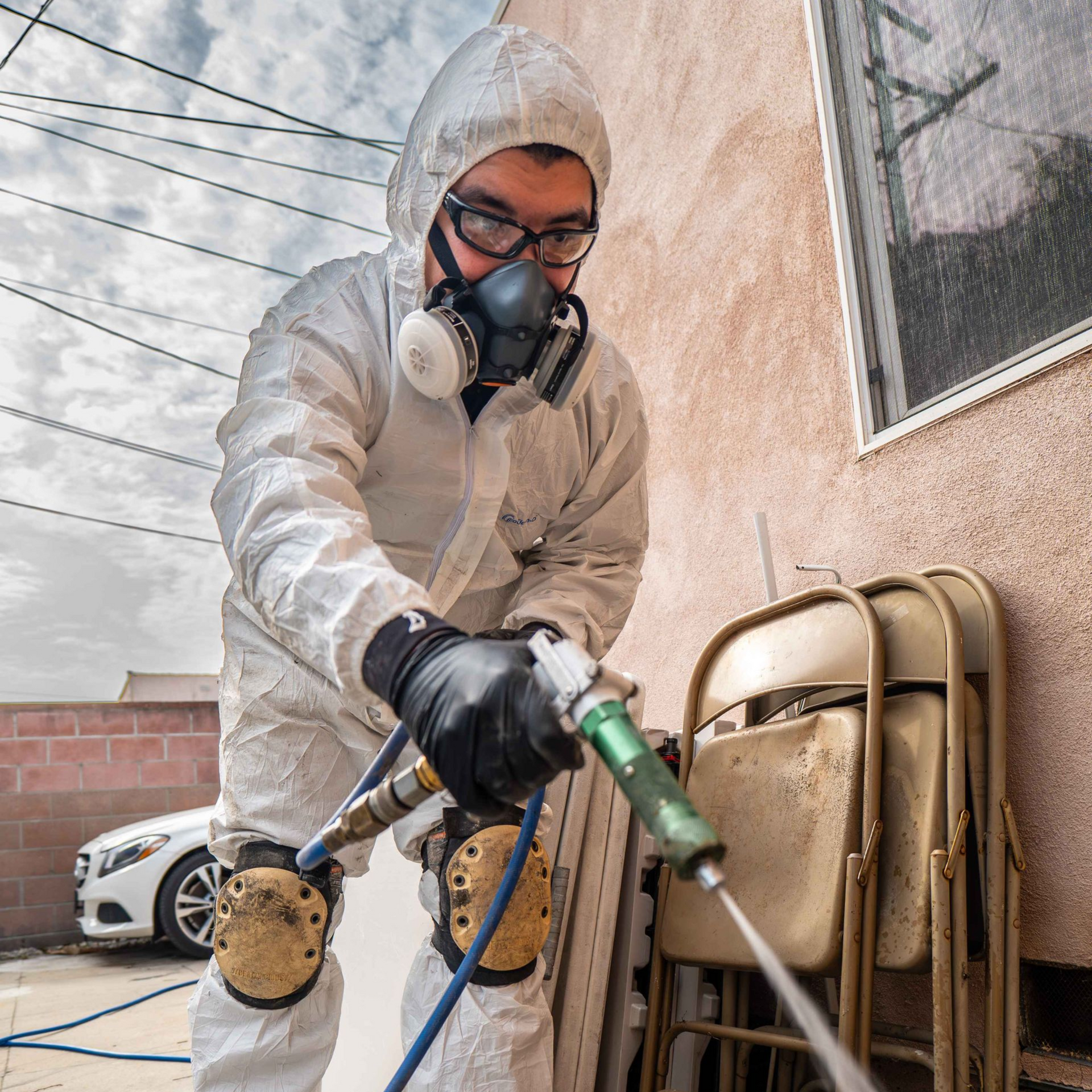 Person in protective suit spraying an insecticide