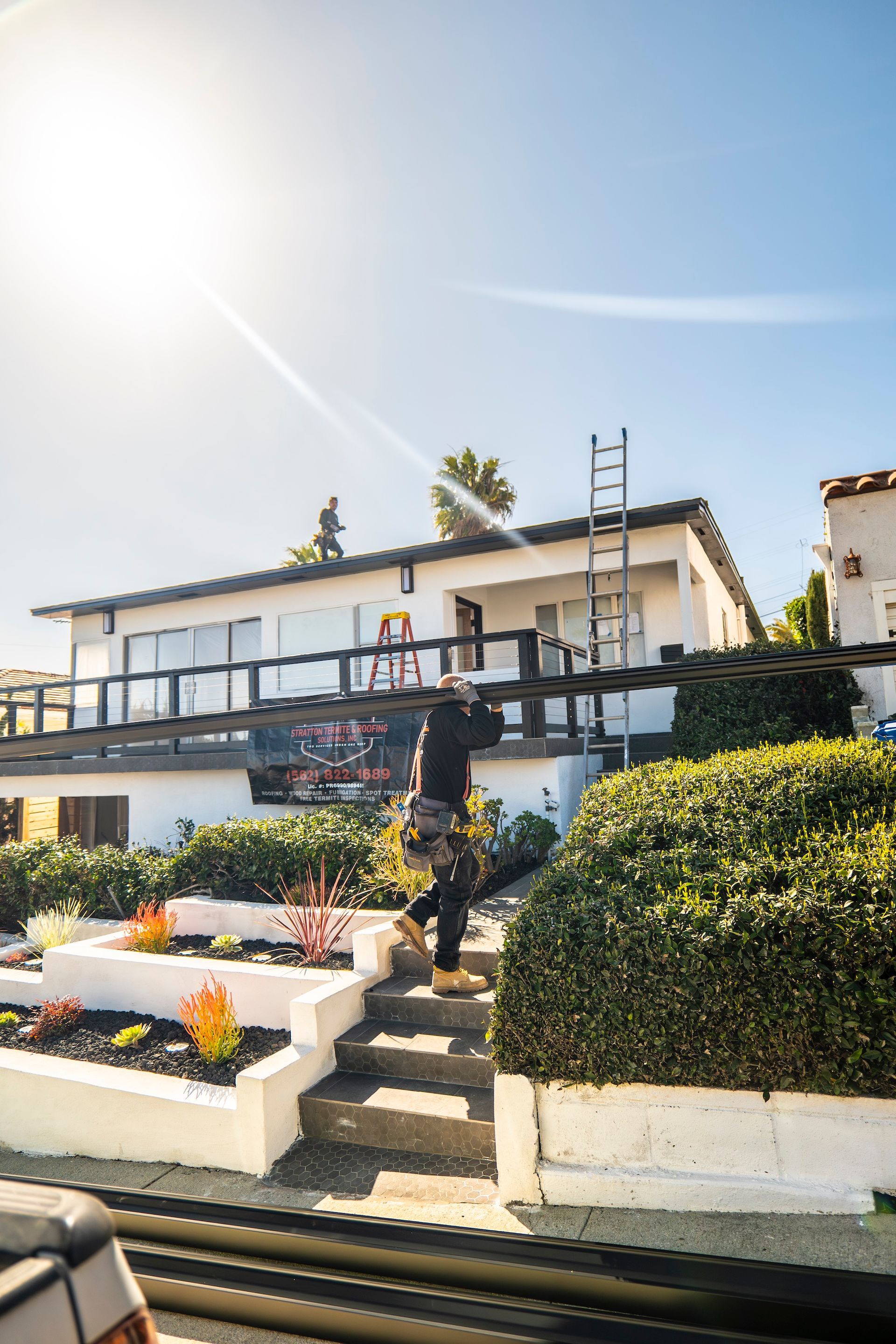 A man is standing on a ladder in front of a house.