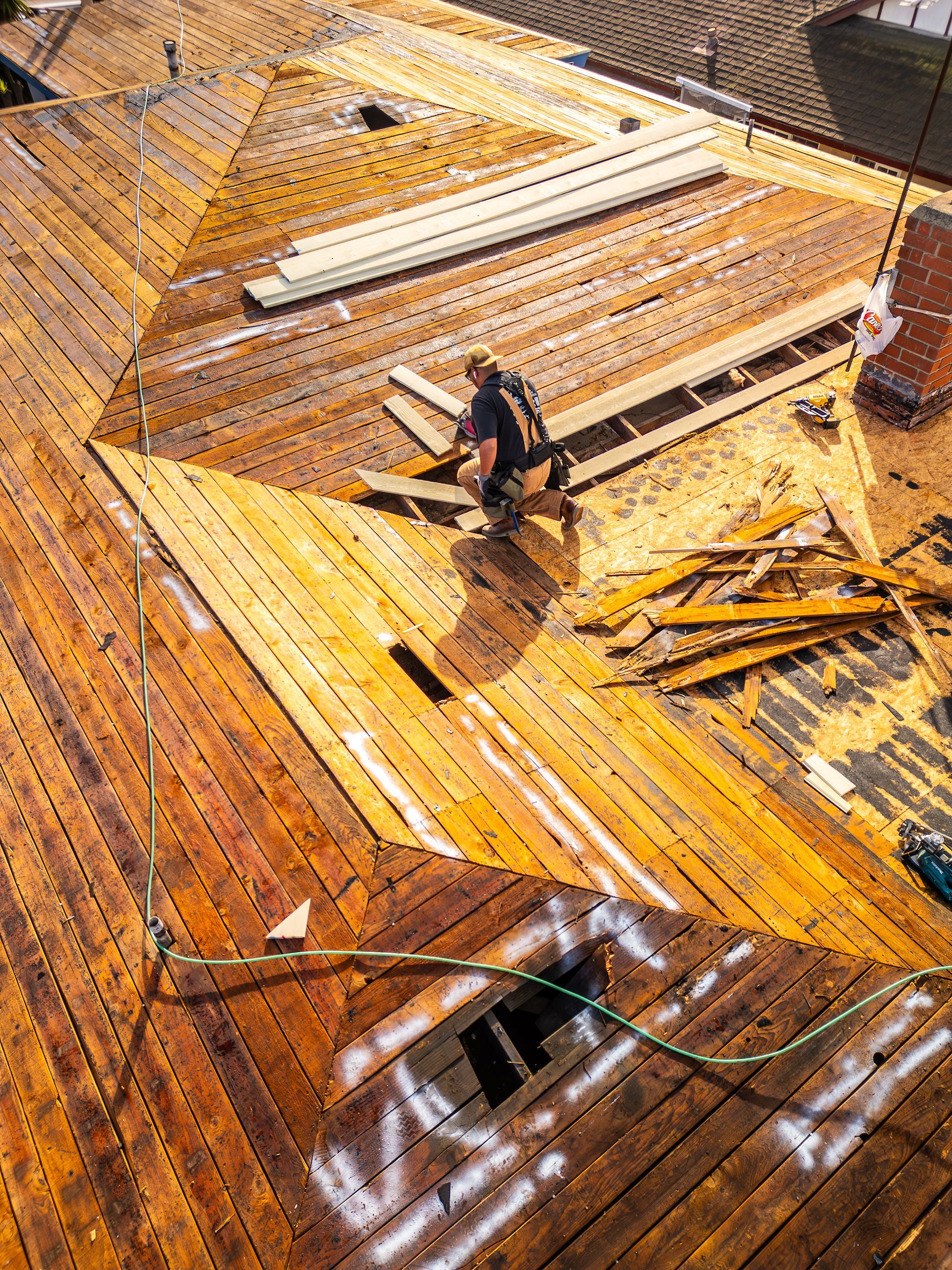 An aerial view of a man working on a wooden roof.