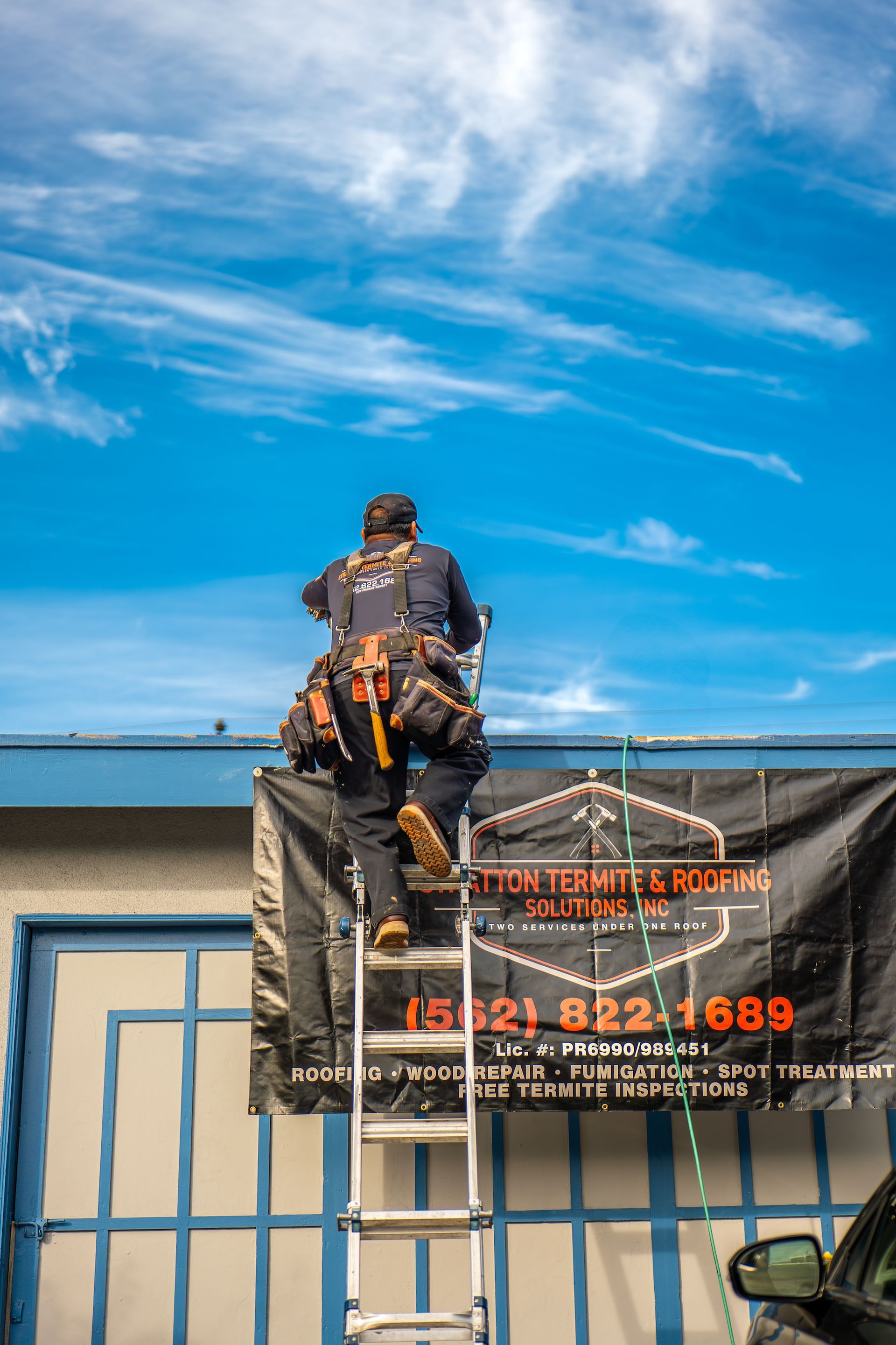 A man is standing on a ladder on top of a building.