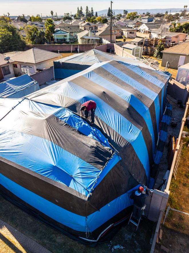 An aerial view of a building covered in blue tarps
