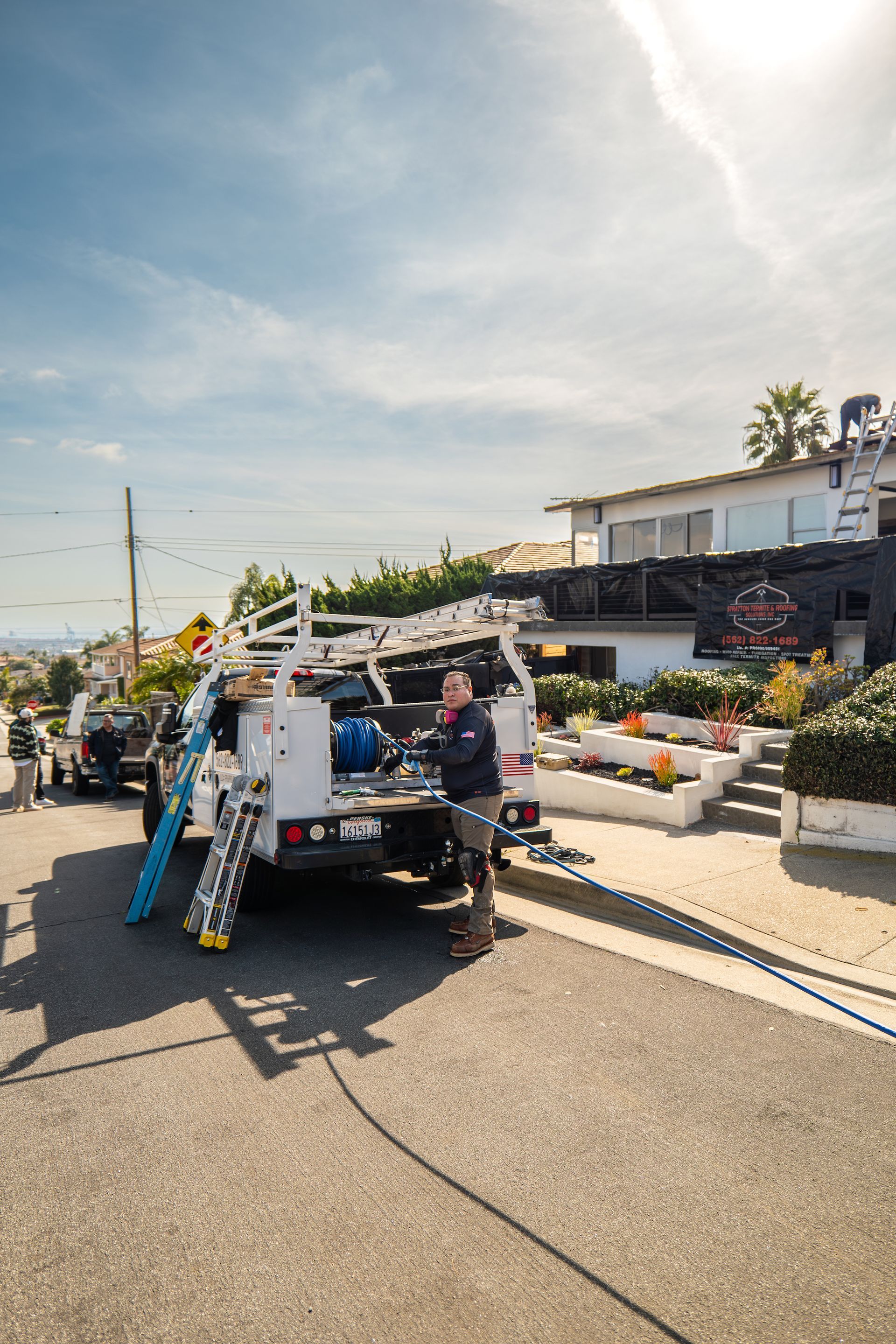 A man is standing next to a truck with a ladder in the back.