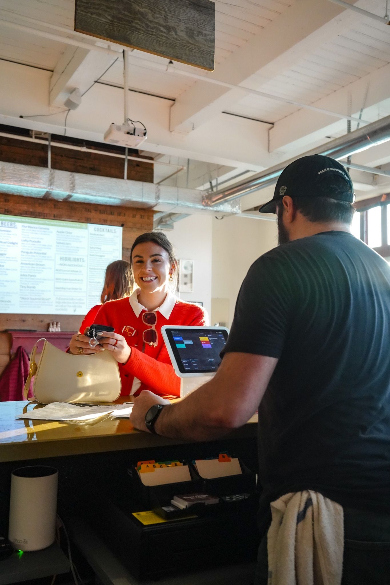 A man and a woman are standing at a counter in a restaurant and bar