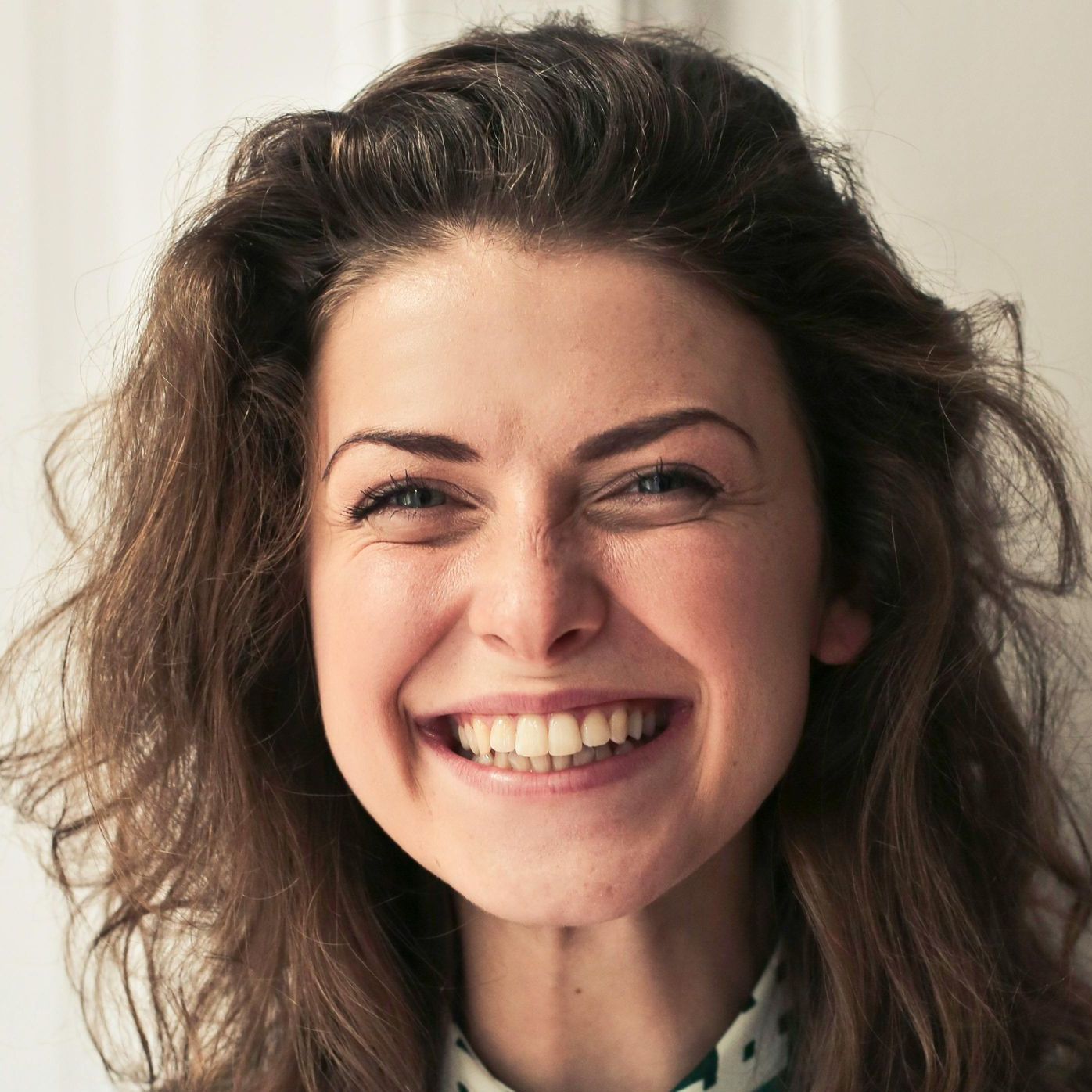 A woman with long hair is smiling and looking at the camera.