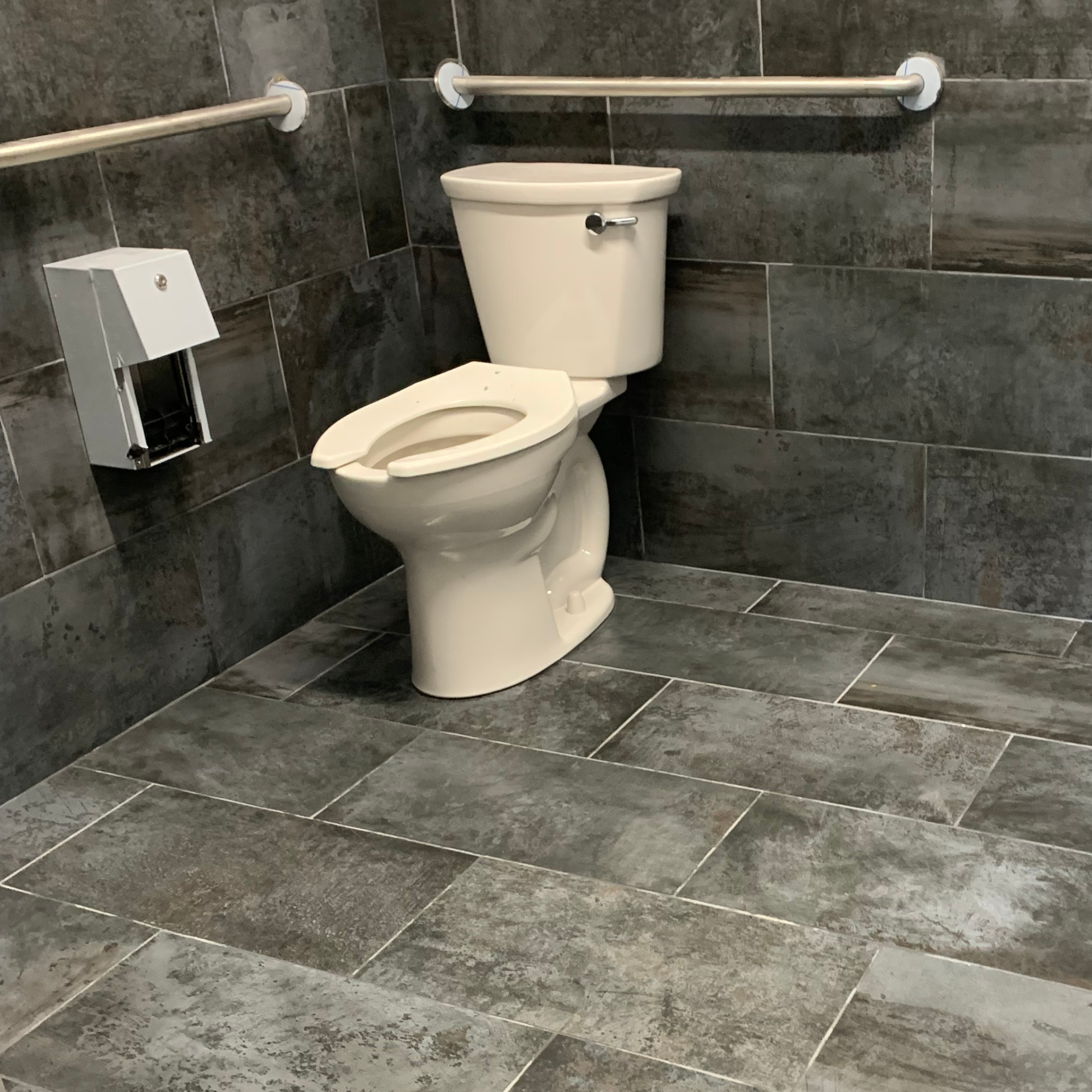 A toilet is sitting on a tiled floor in a bathroom.