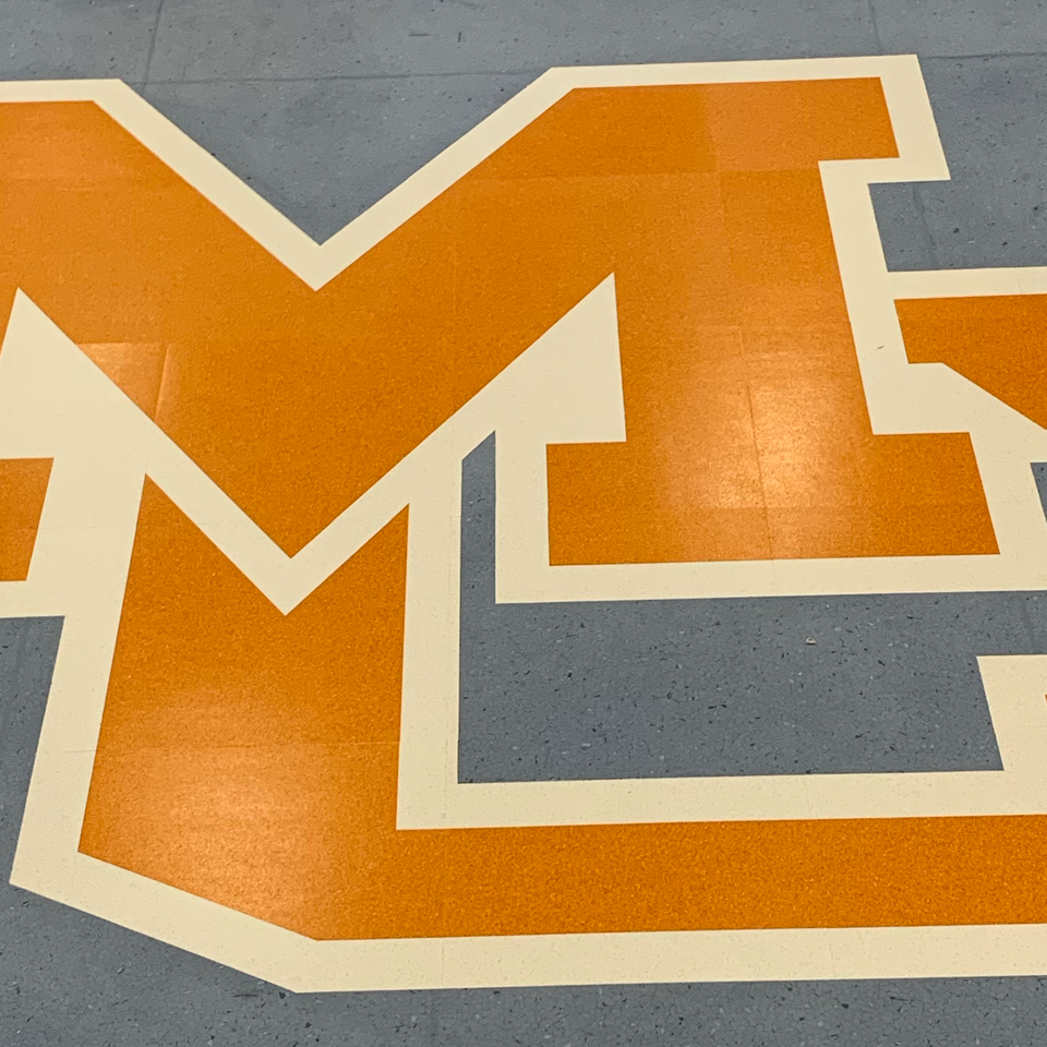 The letter m is painted orange and white on the floor