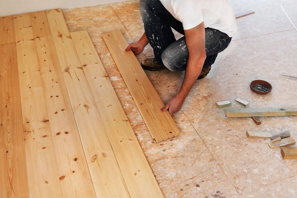 a man is installing a wooden floor in a room .