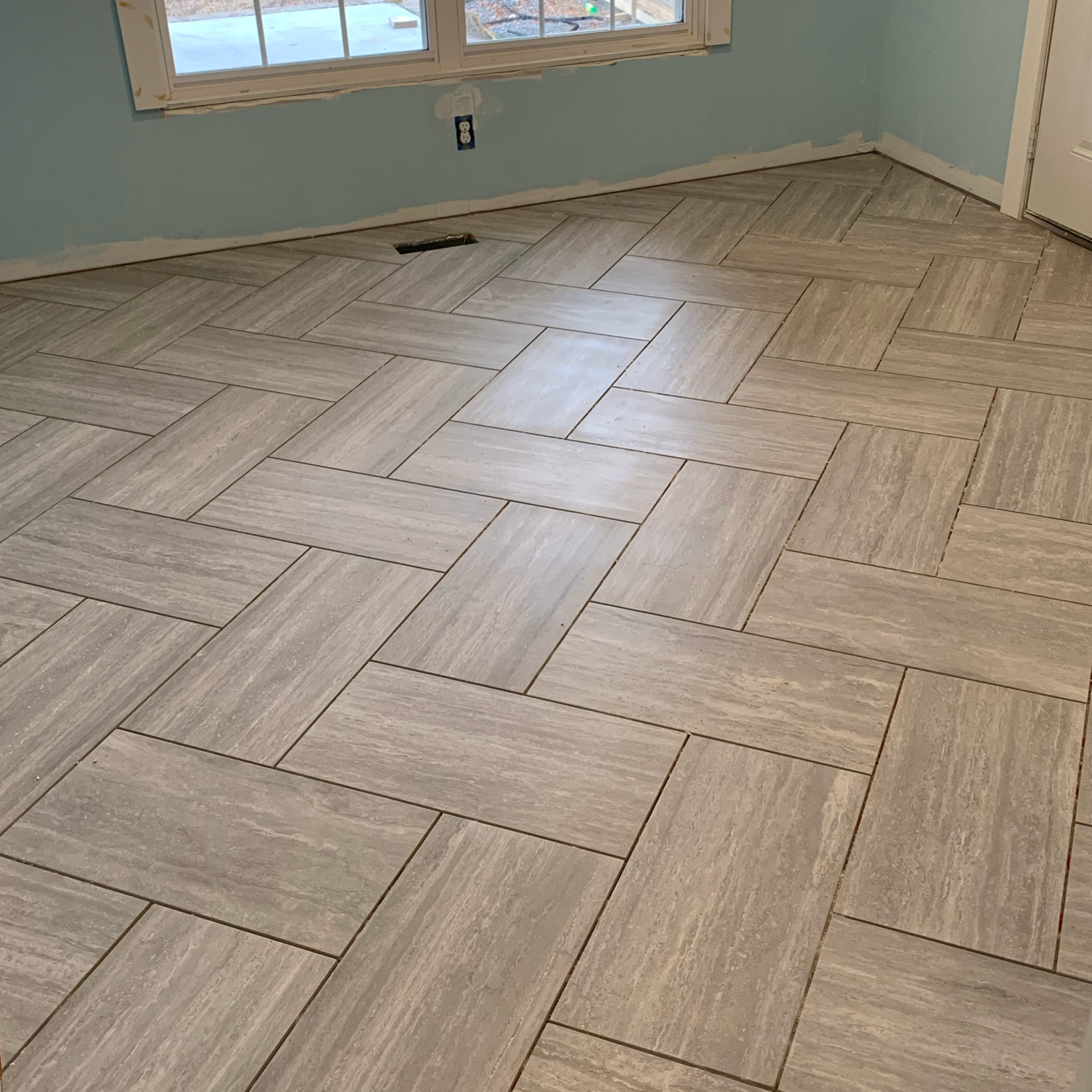 A room with a herringbone tile floor and a window.