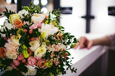 Pastel floral bouquet beside a white altar with a blurred hand in the background