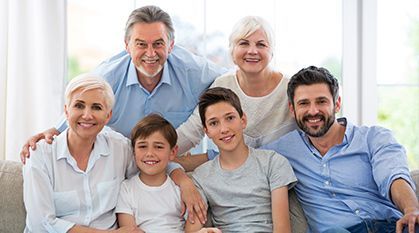 Smiling family of six seated together on a bright couch in a living room