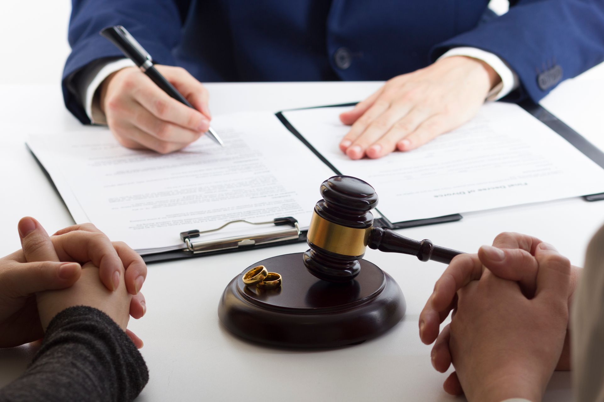 A judge is sitting at a table with two people and a gavel.