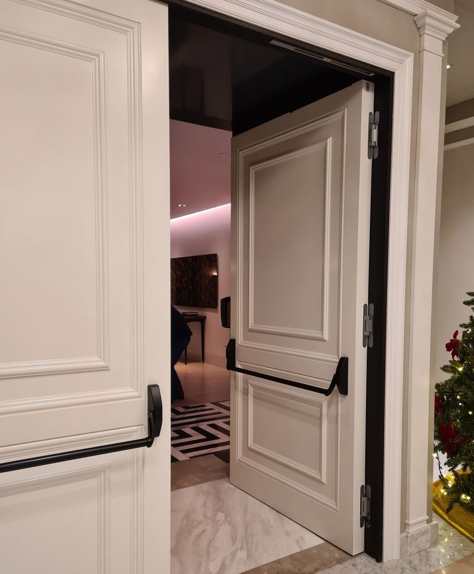 A white door is open to a room with a christmas tree in the background.