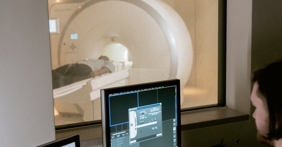 A man is looking at a computer screen in front of a mri machine.