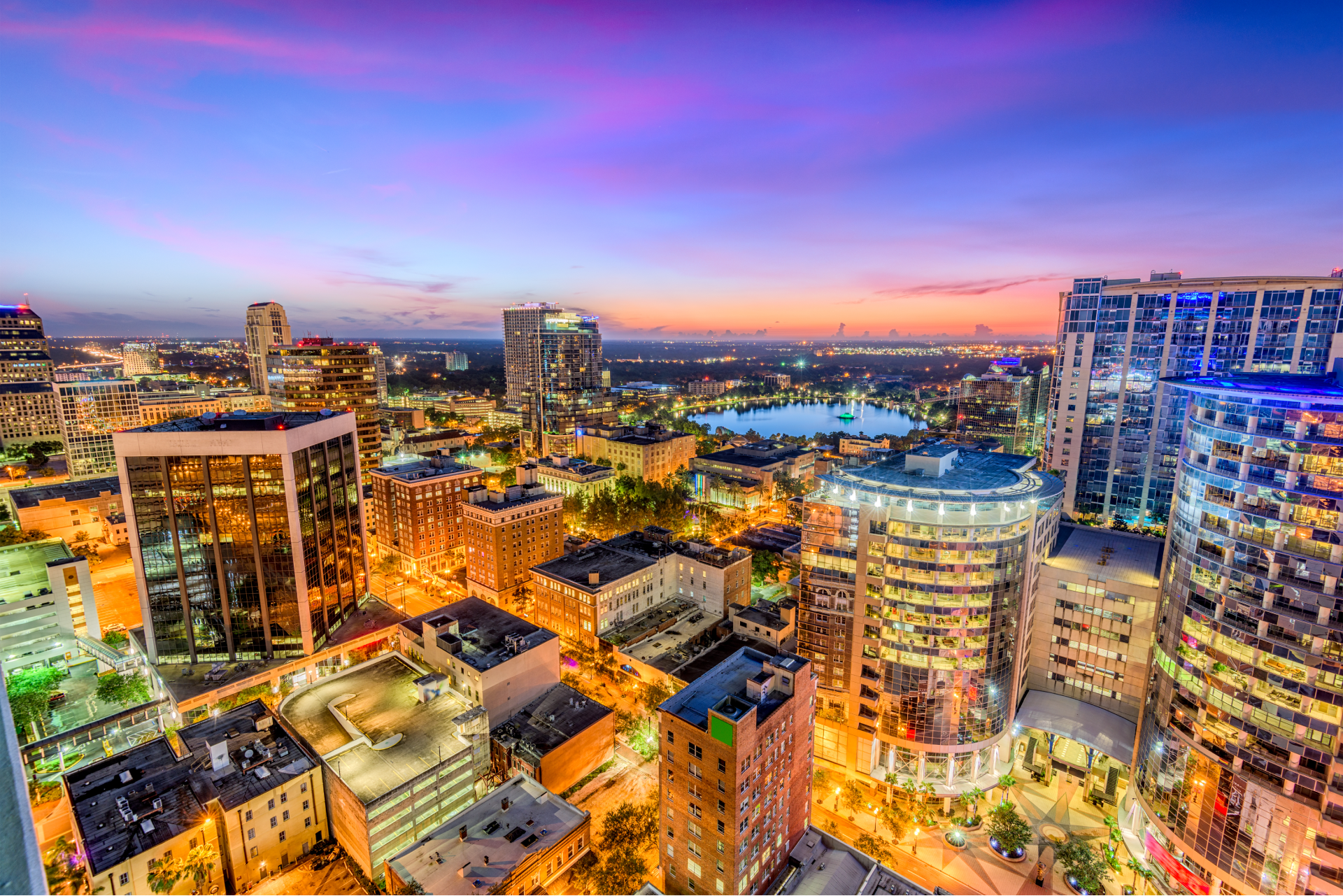 An aerial view of a city at night with a sunset in the background.