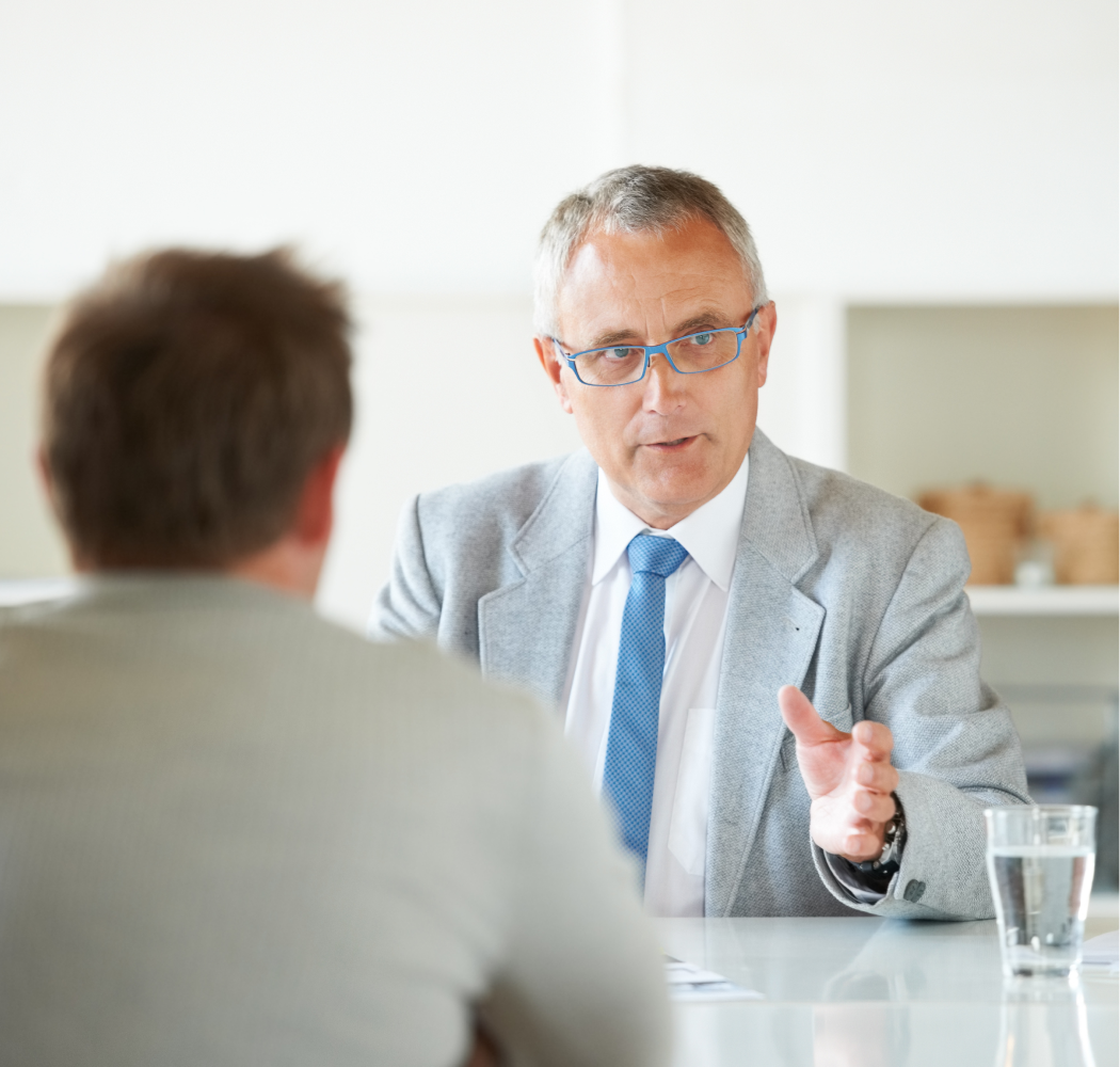 A man in a suit and tie is talking to another man