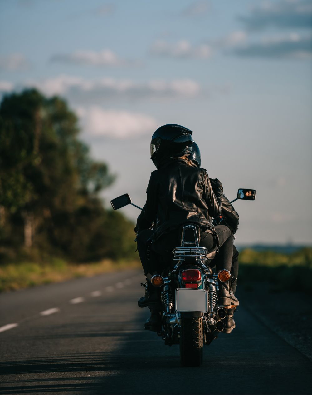 A couple is riding a motorcycle down a road.