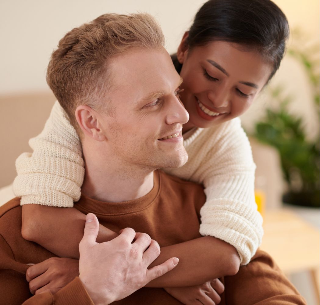 A woman is hugging a man on his back.