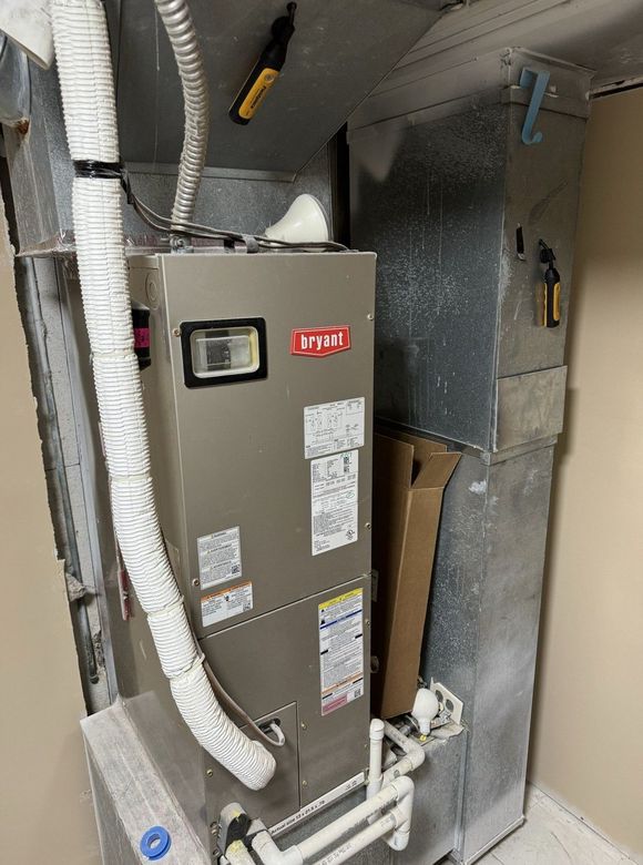 A gray air conditioner is sitting in a room next to a wall.