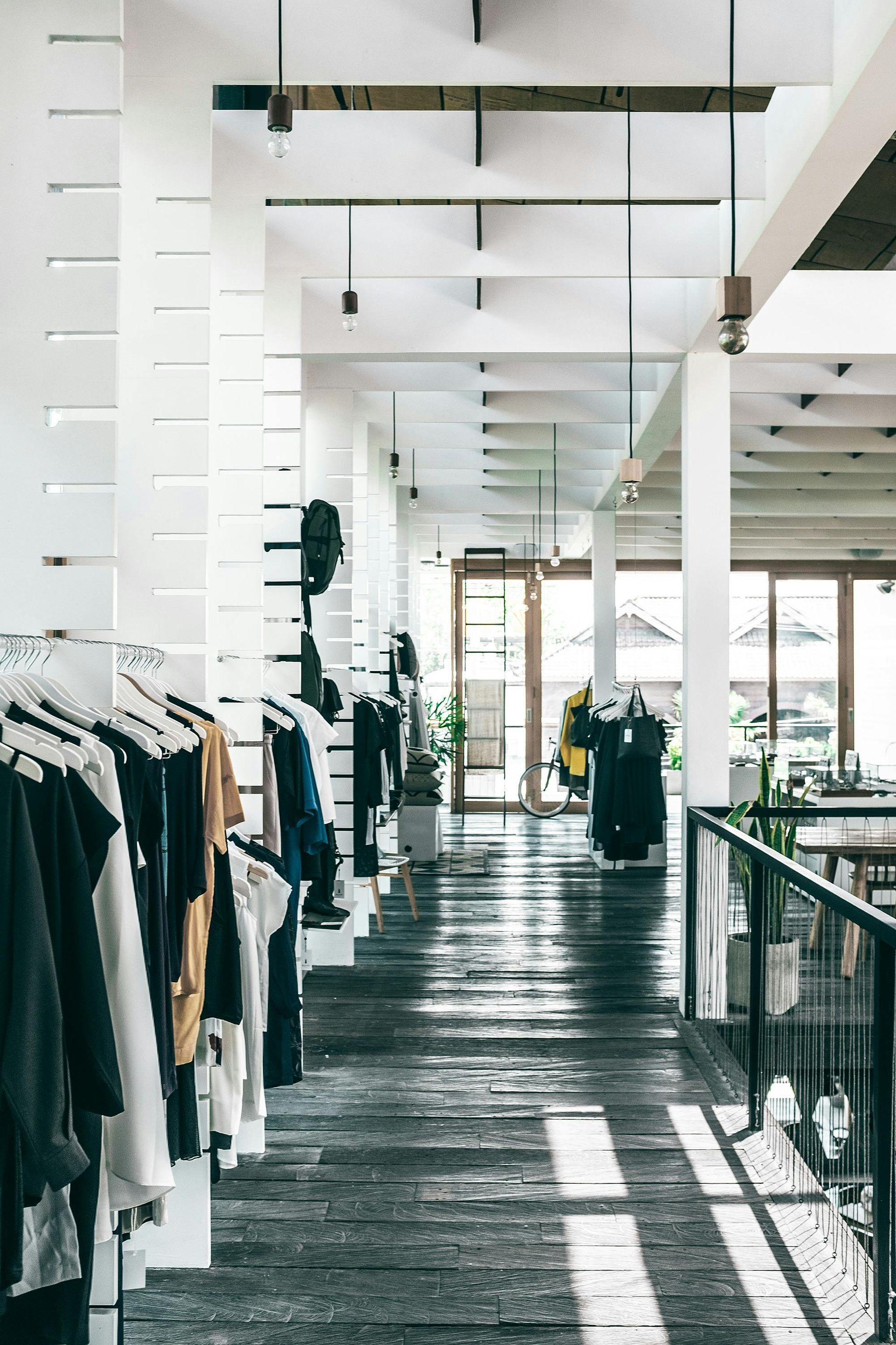 A long hallway in a clothing store with clothes hanging on racks.