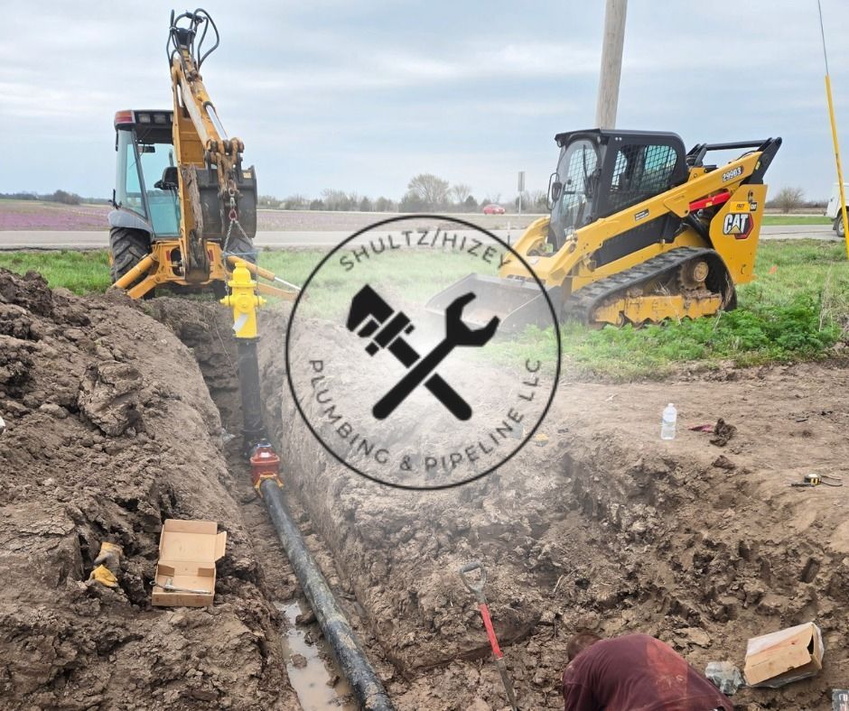Construction site with backhoe and skid steer, workers installing pipe in a trench. Logo overlay: