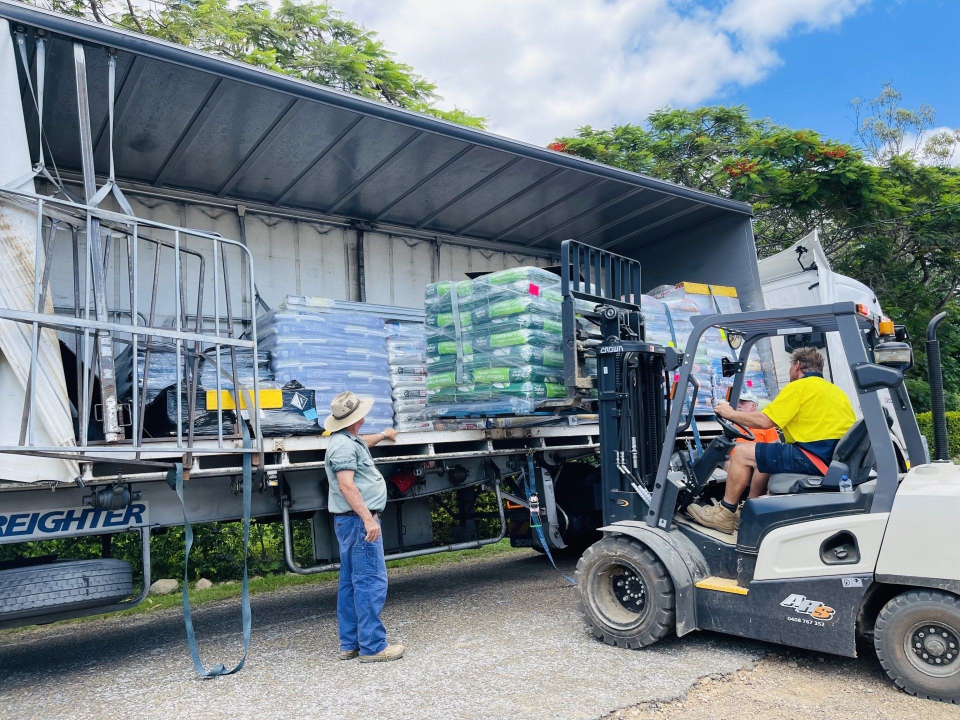 A man is standing next to a forklift loading a truck.
