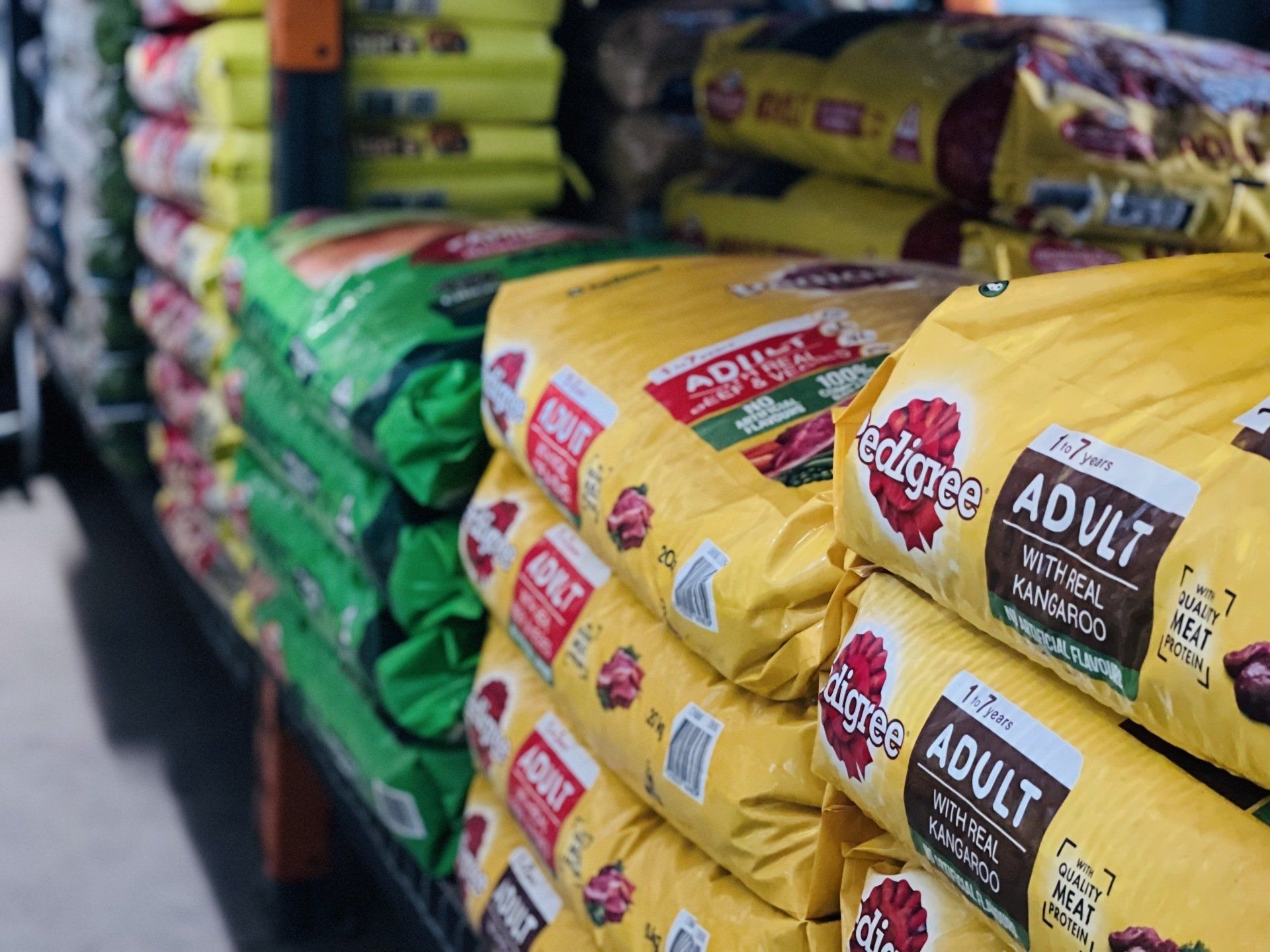 A bunch of bags of dog food are stacked on top of each other in a store.