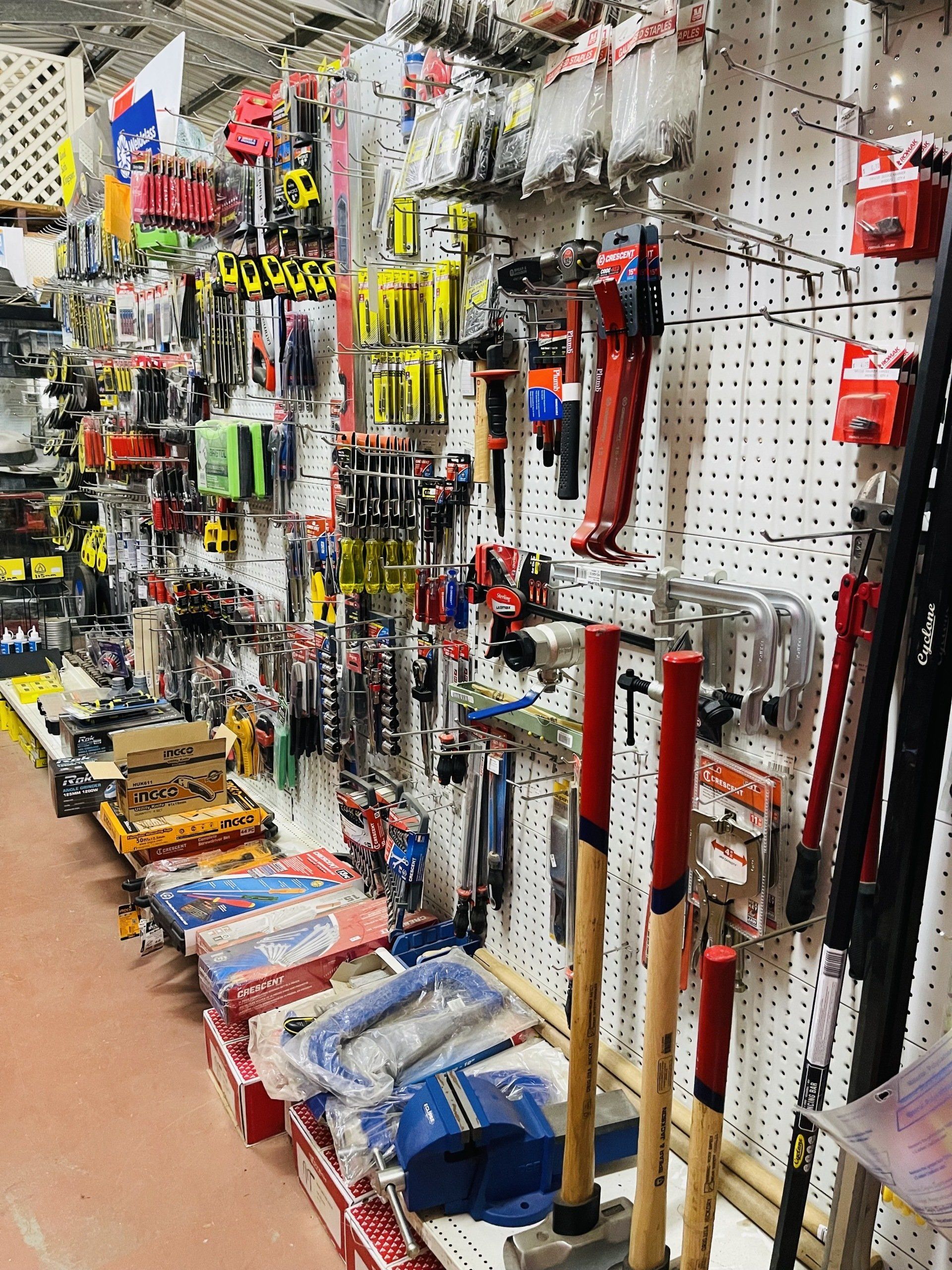 A bunch of tools are hanging on a wall in a store.