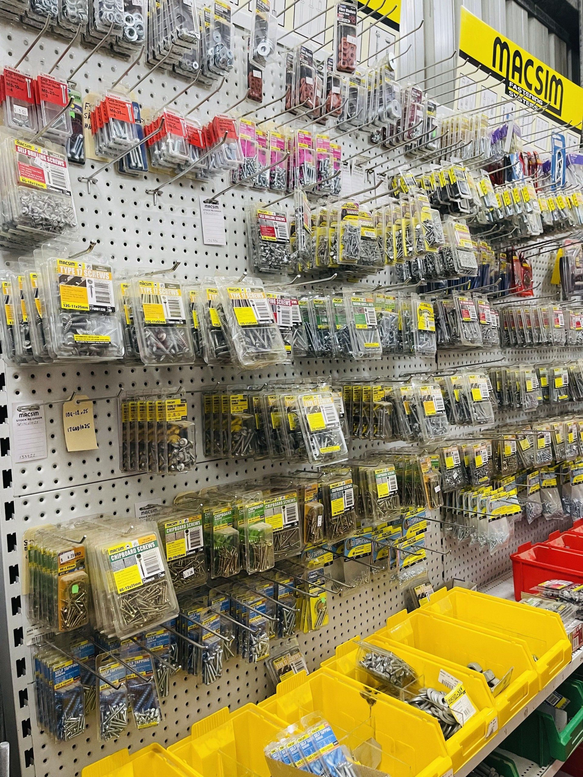 A wall filled with lots of screws and nuts in a hardware store.