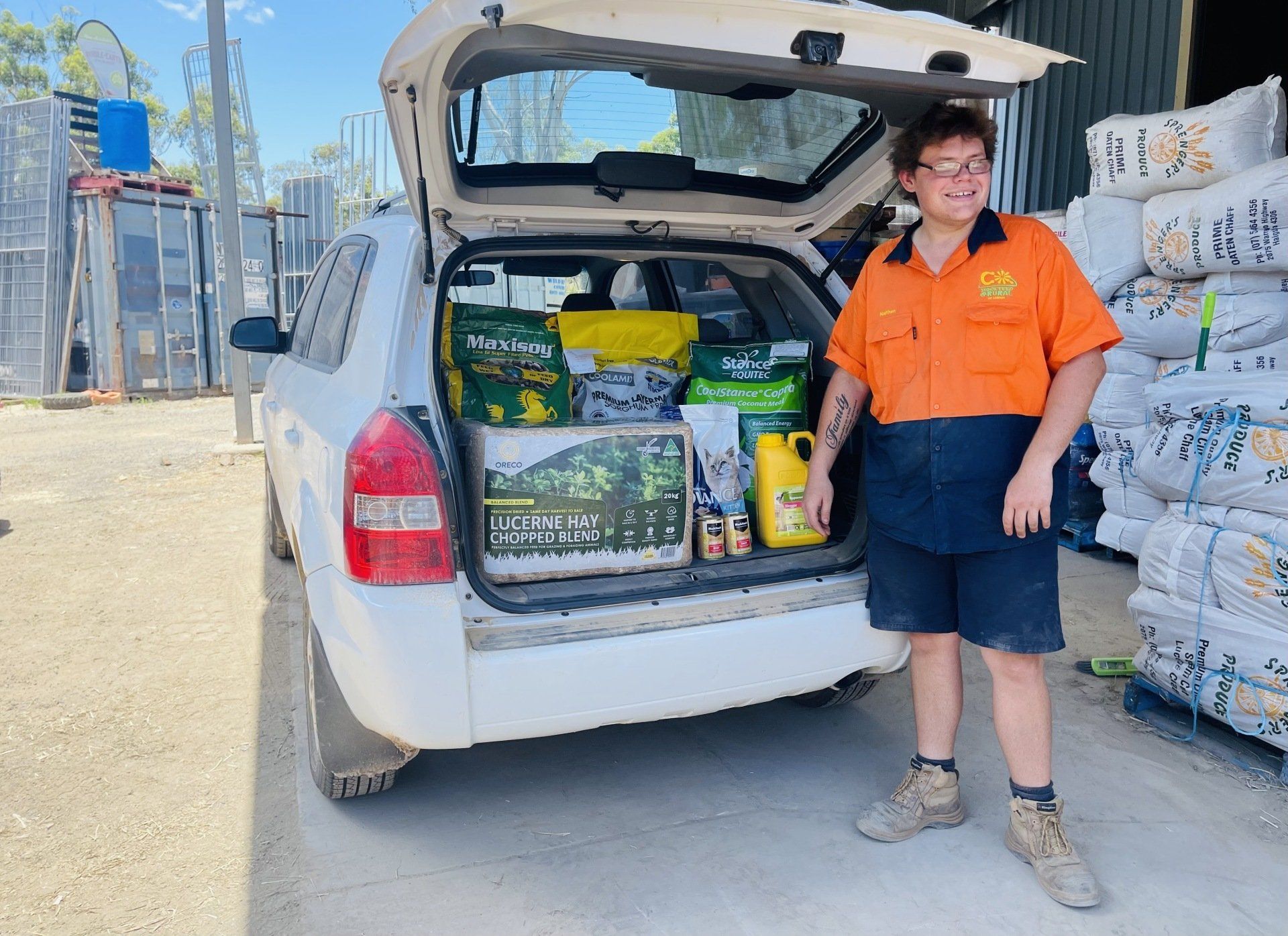 A man is standing in front of a car with the trunk open.