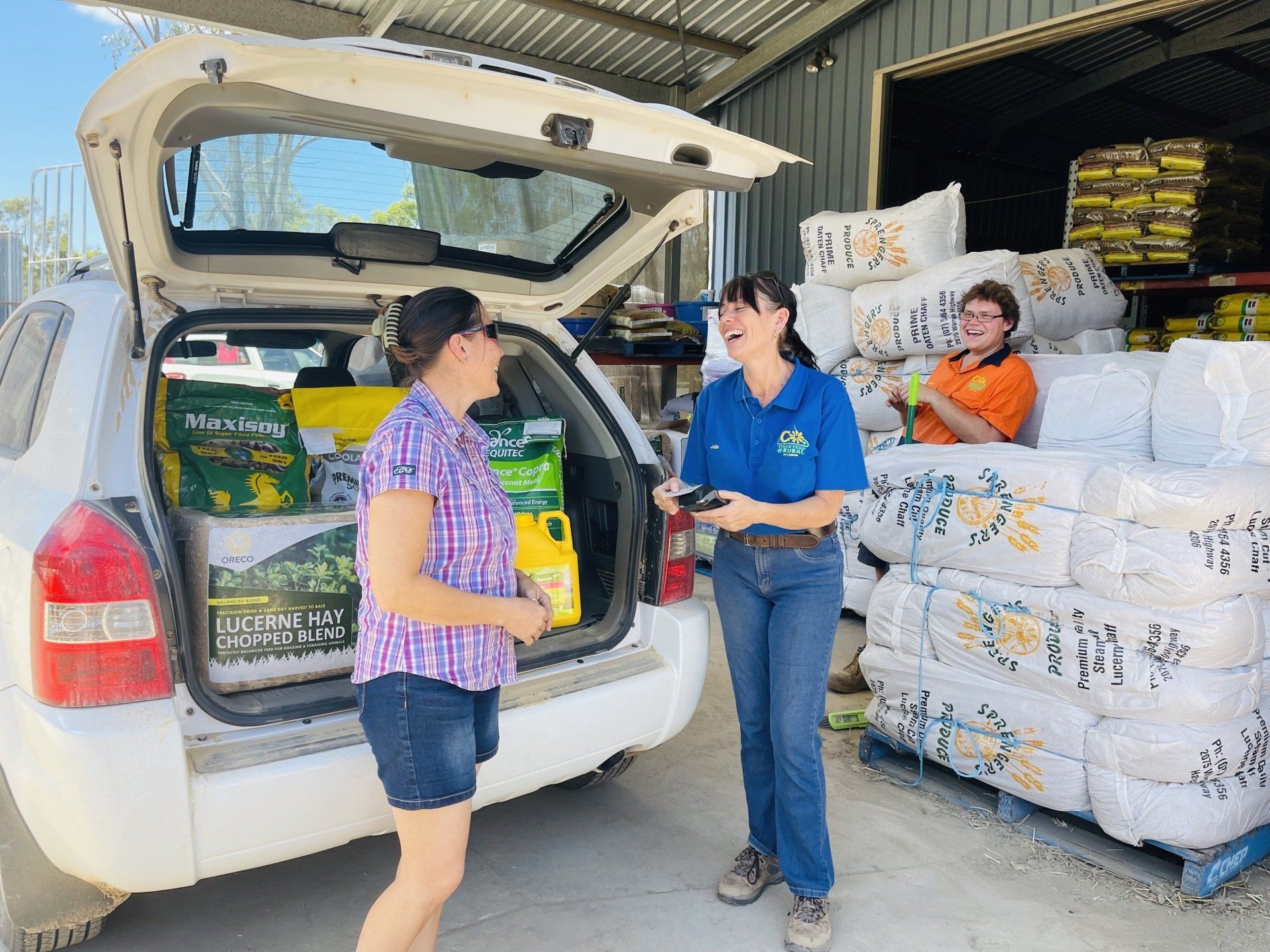Two women are standing next to a car with boxes in the back.
