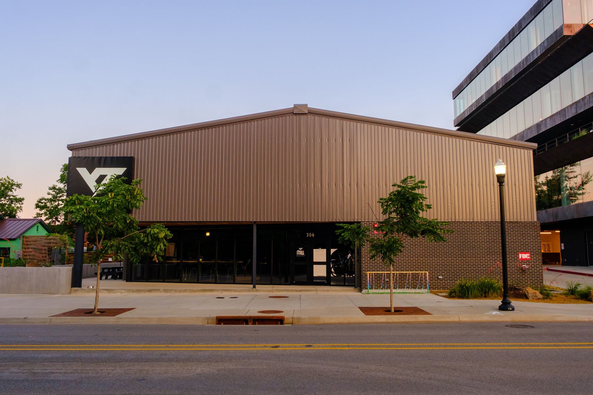 A modern restaurant with wooden siding and large windows. The building features a geometric logo on its facade and is located on a city street.