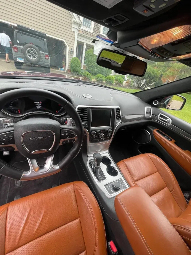 Luxury car interior with tan leather seats, black dashboard, and center console view from the driver’s seat