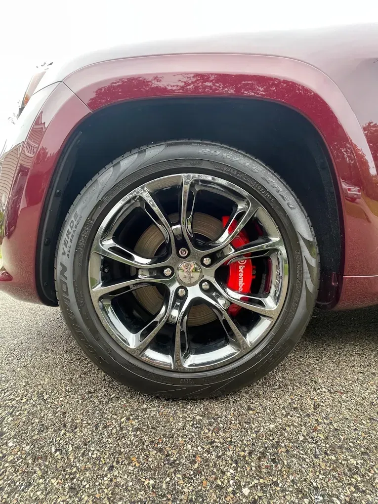 Maroon SUV with polished black alloy wheel and red brake caliper on a wet road