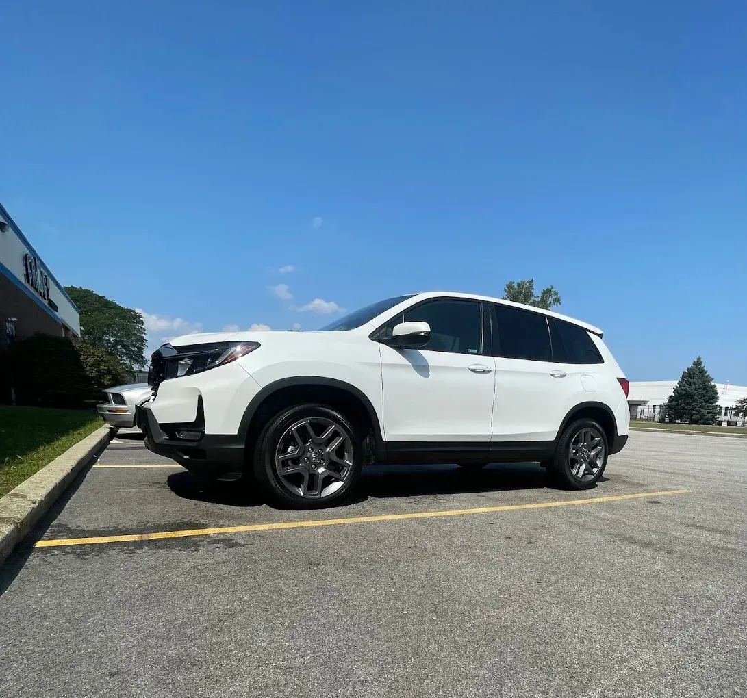 White SUV parked in an outdoor lot under a clear blue sky